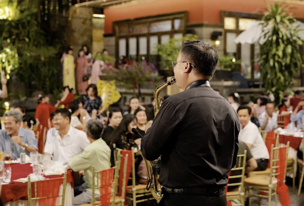 Nghệ sĩ saxophone biểu diễn giữa không gian tiệc sân vườn nhà hàng Mi Sol với khách mời ngồi quanh bàn