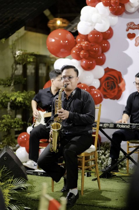 Nghệ sĩ saxophone cùng ban nhạc biểu diễn bên khu vực backdrop tiệc kỷ niệm ngày cưới